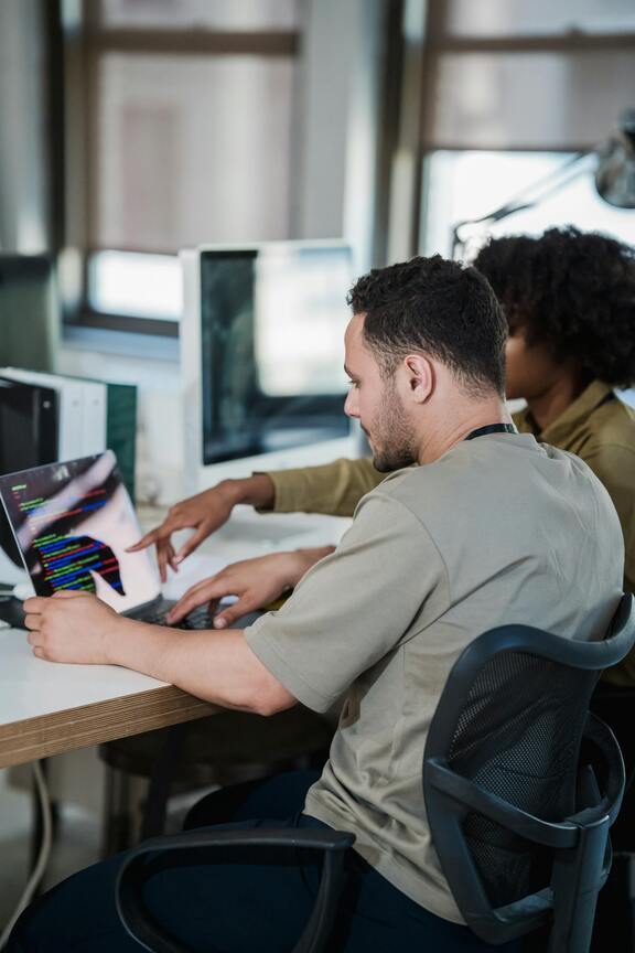 Two students discussing a learning topic displayed on a laptop